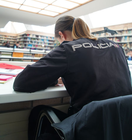 Mujer policía, estudiando en una biblioteca.