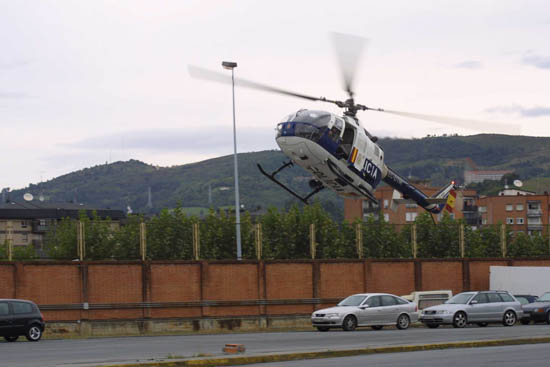 Helicóptero de Policía Nacional realizando una maniobra de despegue desde un aparcamiento.