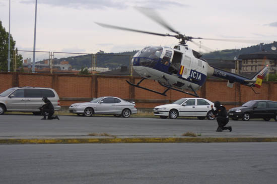 Helicóptero de Policía Nacional en vuelo de poca altura con dos miembros de Unidades Especiales dando cobertura al aparato.