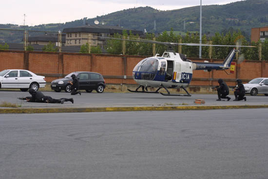 Helicóptero de Policía Nacional en vuelo de poca altura con varios miembros de Unidades Especiales dando cobertura al despliegue humano.