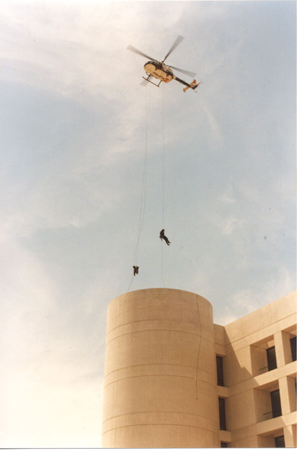 Helicóptero de Policía Nacional sobre un edificio con dos miembros de Unidades Especiales en el exterior, asaltando el edificio en rapel.