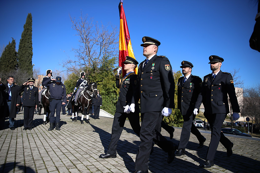 Cuatro hombres uniformados desfilando portando uno de ellos la bandera nacional. 
