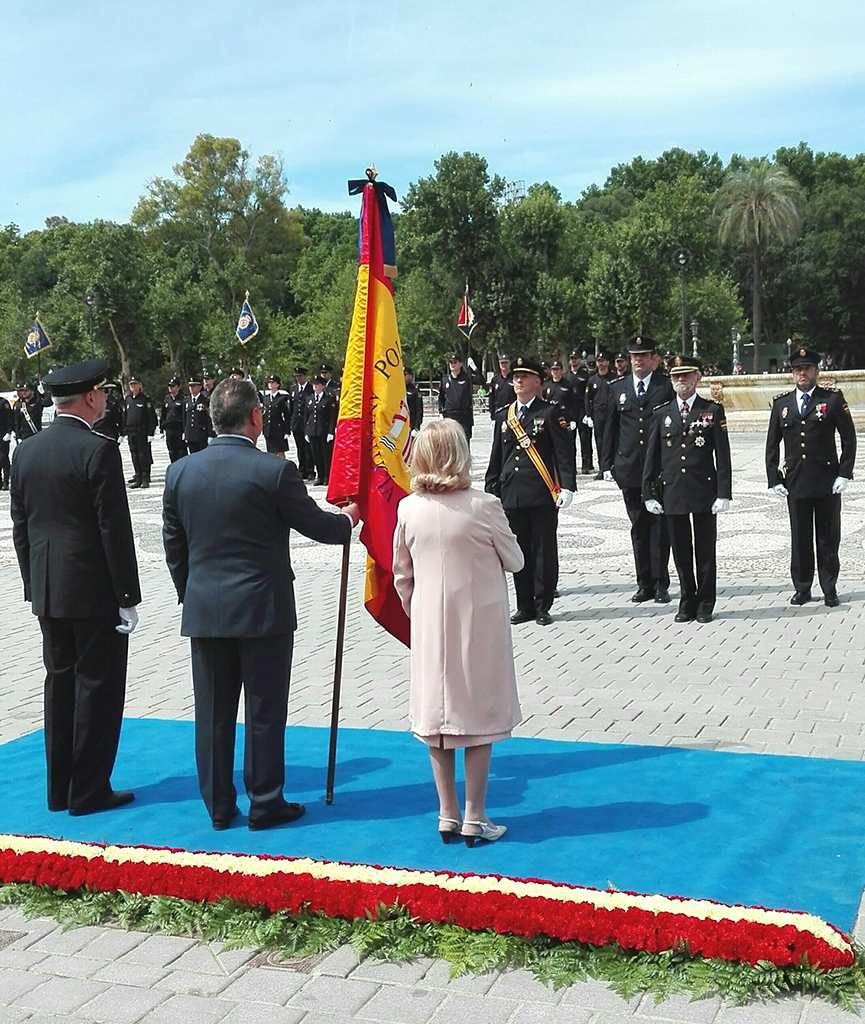El Ministro del Interior sujetando la bandera de España frente a un grupo de Policías Nacionales en formación.