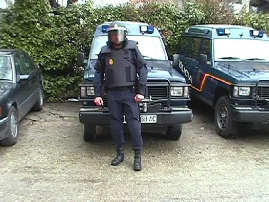 Policía ataviado con el chaleco anti trauma y el casco de protección con la visera bajada, frente a vehículo Nissan Patrol de la Unidad.