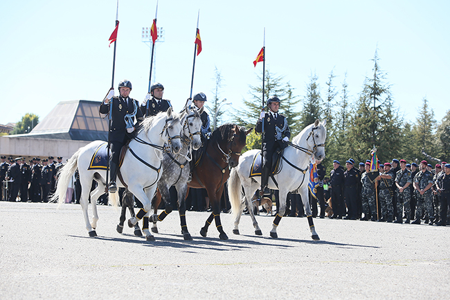 Desfile de caballería compuesto por cuatro integrantes perfectamente alineados. De fondo se observan policías uniformados de distintas unidades.
