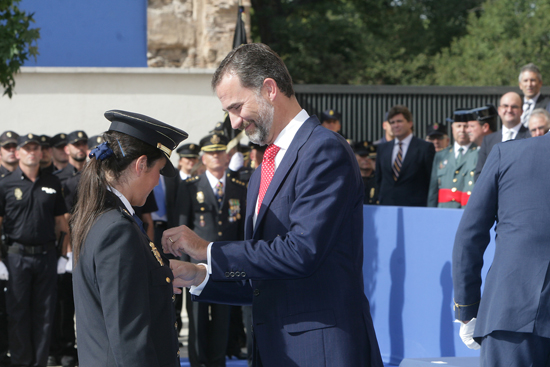 S.A.R. Don Felipe colocando una condecoración a una Policía Nacional vestida con el uniforme de gala en la guerrera..