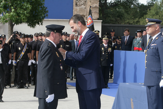 S.A.R. Don Felipe haciendo entrega de una condecoración a un Policía Nacional vestido con el uniforme de gala.