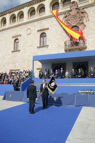 El Alcalde de Alcalá de Henares entrega un estandarte de la Policía Nacional al Director Adjunto Operativo, delante del palco de autoridades.