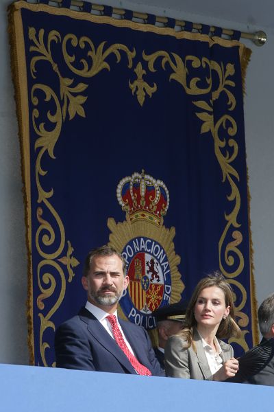 S.A.R. Don Felipe y Doña Leticia en el palco de autoridades y de fondo un tapiz con el escudo de la Policía Nacional.