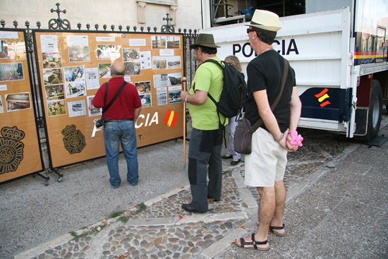 Varios visitantes mirando un tablón con diversas fotos e información sobre la Policía Nacional.