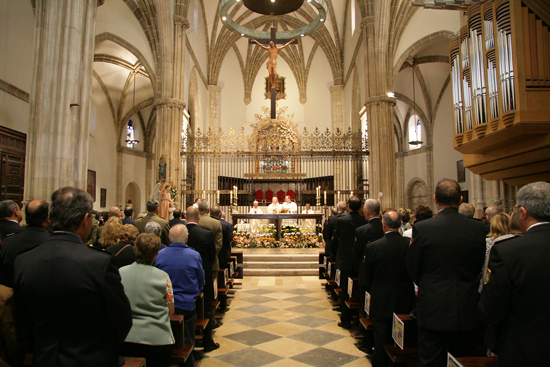 En el altar, el Obispo Complutense celebrando misa por los Ángeles Custodios. Asistentes a la misa en los bancos de espalda.