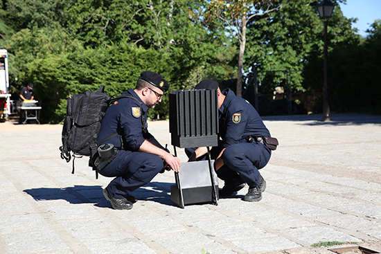 Dos policías uniformados agachados manejando material para la preparación de un evento.