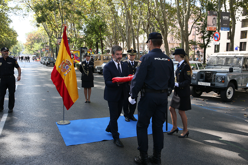 El Director General de la Policía Ignacio Cosidó Gutiérrez, hace entrega de la bandera española a un representate de la  la Policía Nacional.