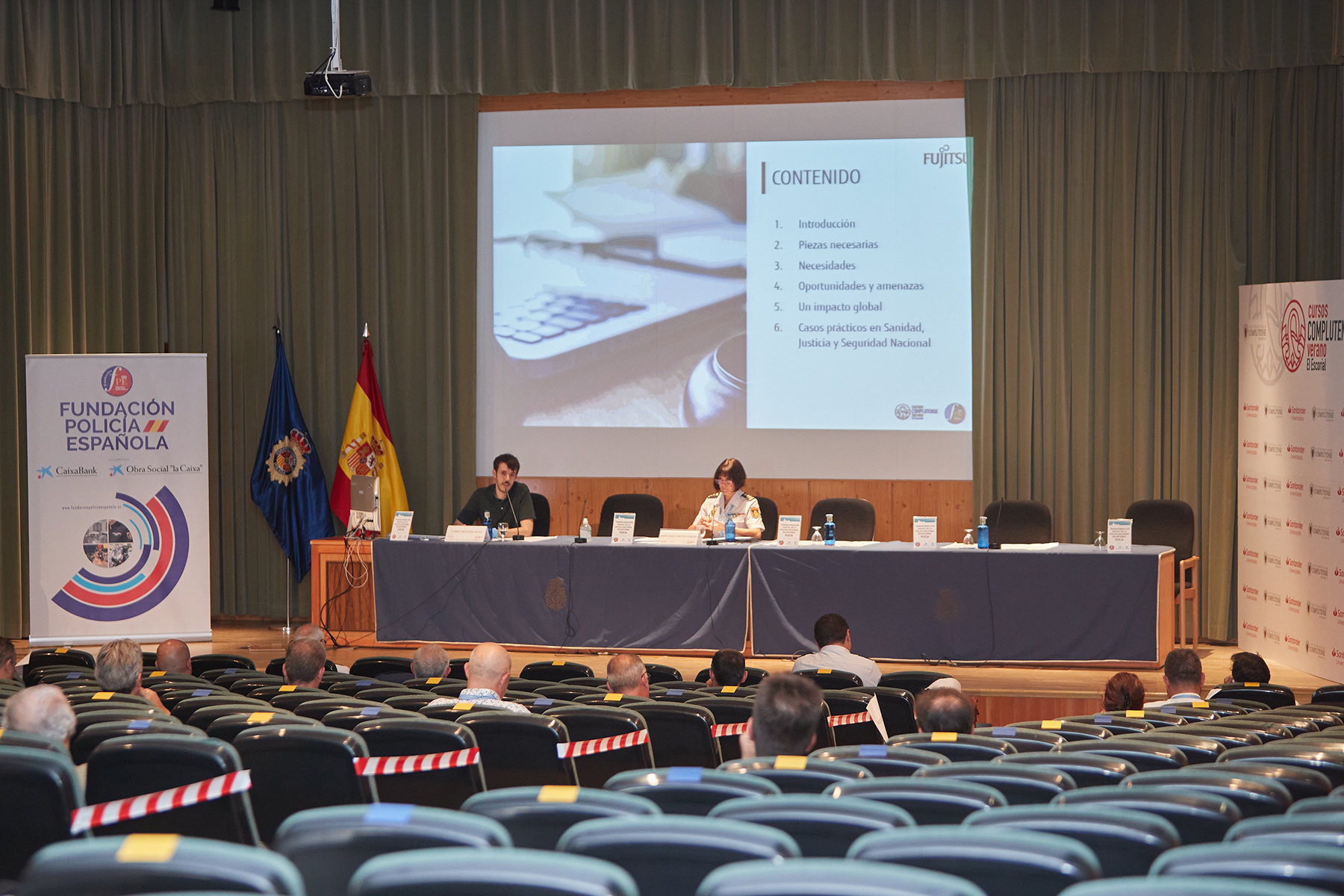 Primer plano en la mesa de ponentes de la Comisaría María Jesús Cantos Cebrian, junto a un hombre. 