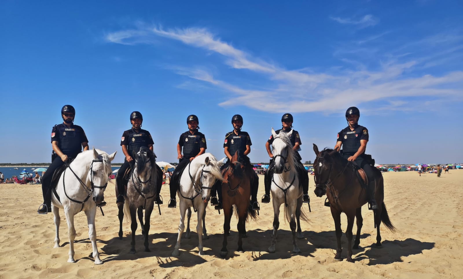 Seis policías montados a caballo sobre la arena de la playa