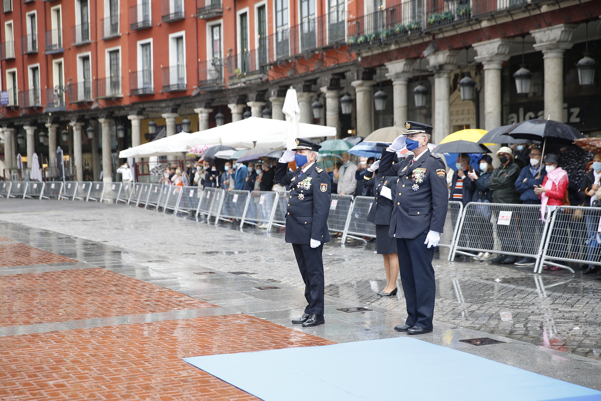 Tres policías uniformados (dos hombres y una mujer) en posición de firmes y saludando. 