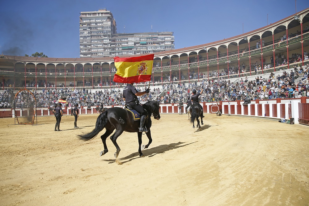 Diversos policías uniformados de Caballería portando uno de ellos la bandera de España. 