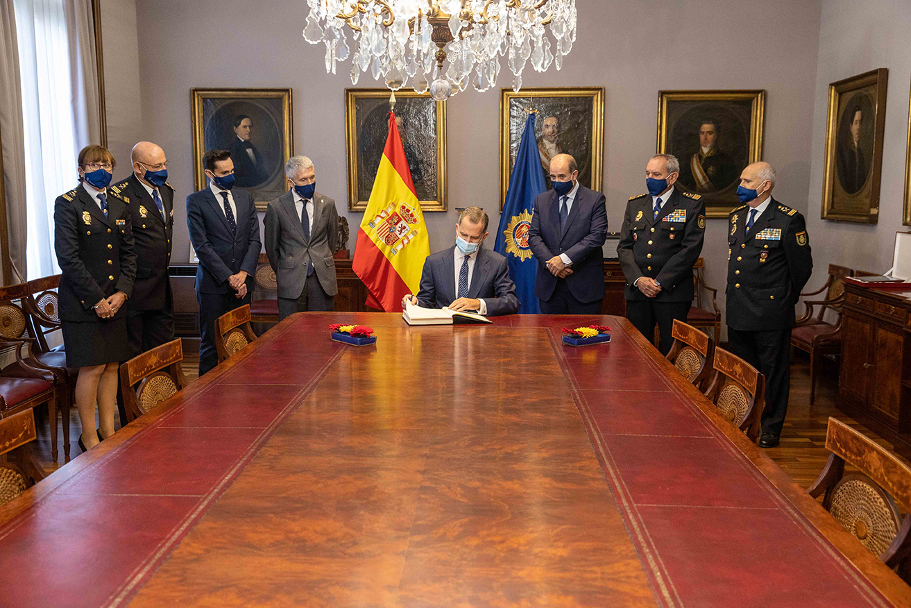 S.M. el Rey sentado en la mesa. En pie, junto a él, Ministro del Interior, Secretario de Estado de Seguridad y la cúpula de la Policía Nacional.