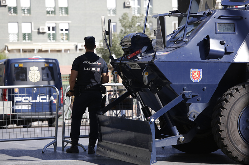 Fotografía de un agente de la Policía Nacional pertenecioente a la Unidad de Intervención Policial junto con un vehículo blindado.