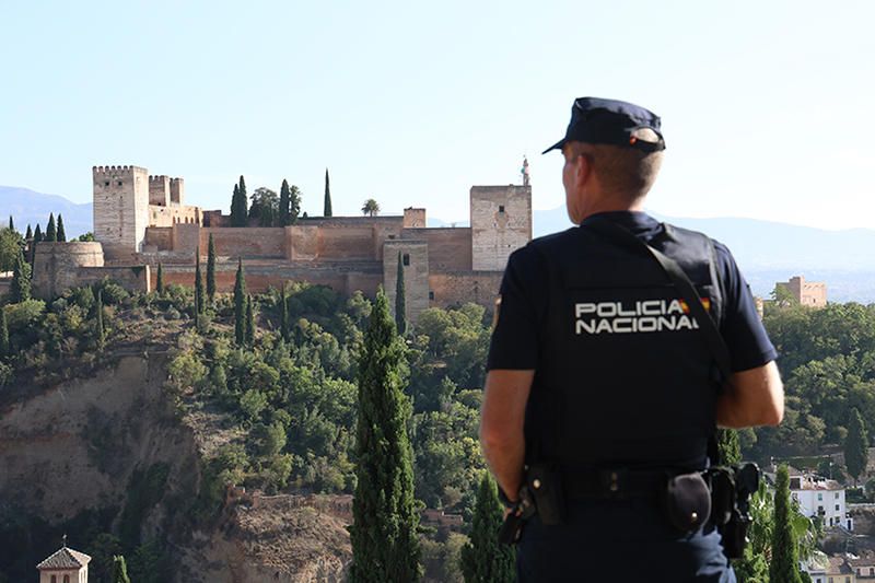 Agente de Policía Nacional realizando labores de vigilancia, al fondo se puede ver la Alhambra