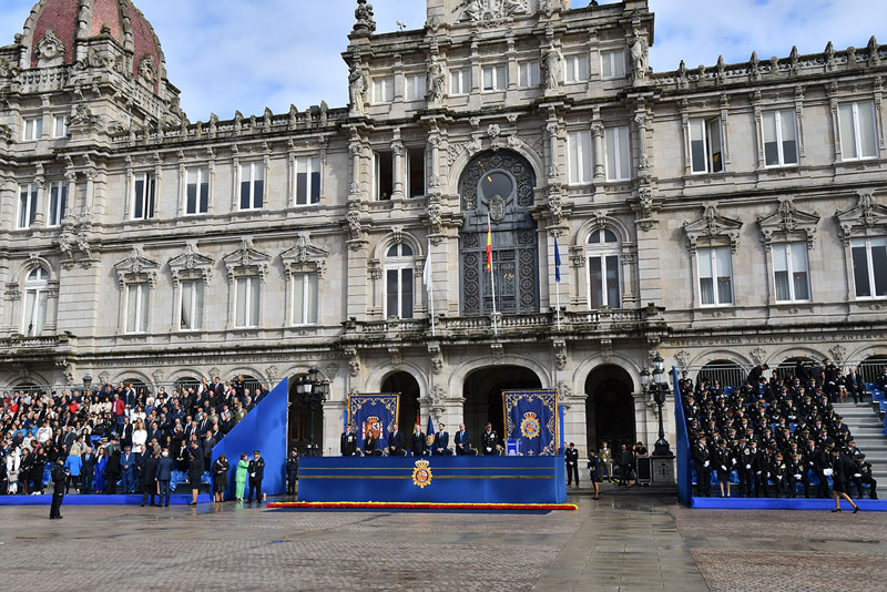 Fotografia en la que puede observar la Plaza María Pita de A Coruña  decoradas con las banderas de Policía Nacional y los asistente al Acto Central.