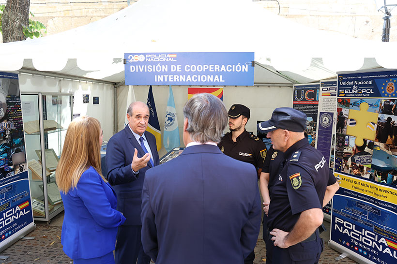 Fotografía en la que se puede ver como el Director General de la Policía habla con policías nacionales en un stand de la exposición.