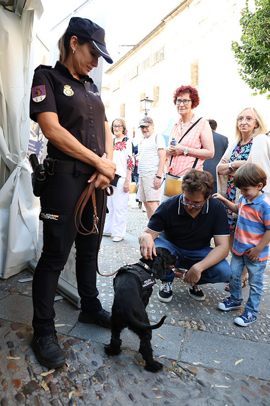 Fotografía de un policía perteneciente a la Unidad Especial de Guías Caninos junto con su can, saludan a las personas que acuden al stand