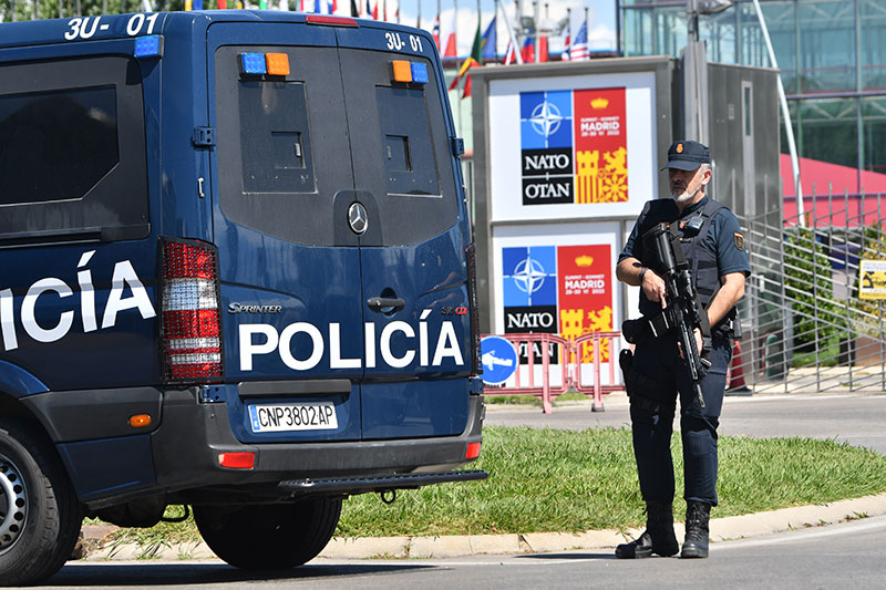 Agente de la Policía Nacional, con el armamento reglamentario,  junto a furgoneta policial.