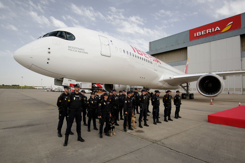 Miembros de la Policía Nacional, en formación, junto al avión de Iberia con el rótulo del bicentenario.