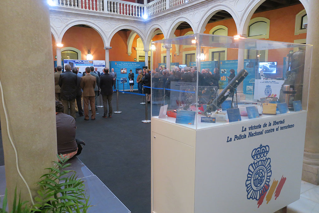 Imagen del acto de inauguración de la exposición, en la que se puede observar una vitrina que contiene un lanzagranadas.