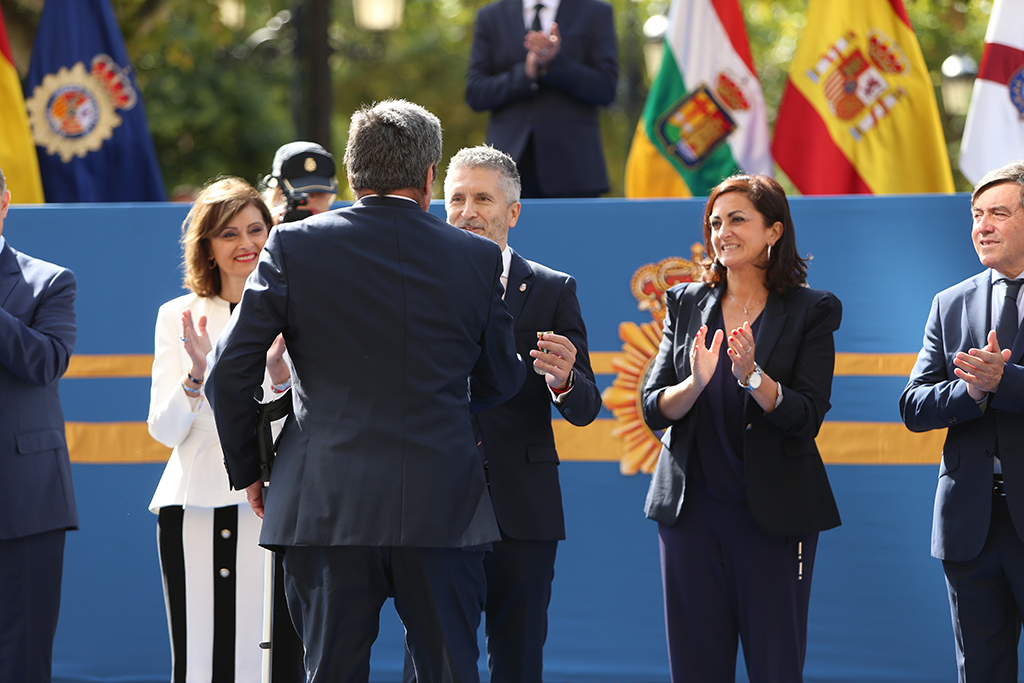 El Ministro del Interior, D. Fernando GRANDE-MARLASKA, saludando a una persona que se encuentra de espaldas junto a diversas autoridades.