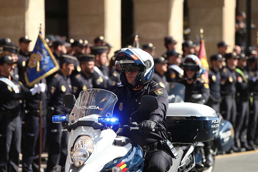 Primer plano de un policía en motocicleta y al fondo policías en formación.