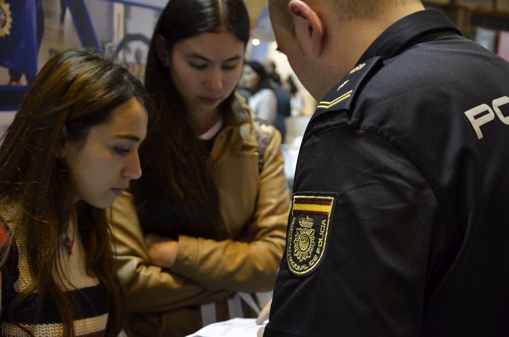 Dos chicas jóvenes escuchando atentamente la información que le proporciona un miembro de la Policía Nacional.