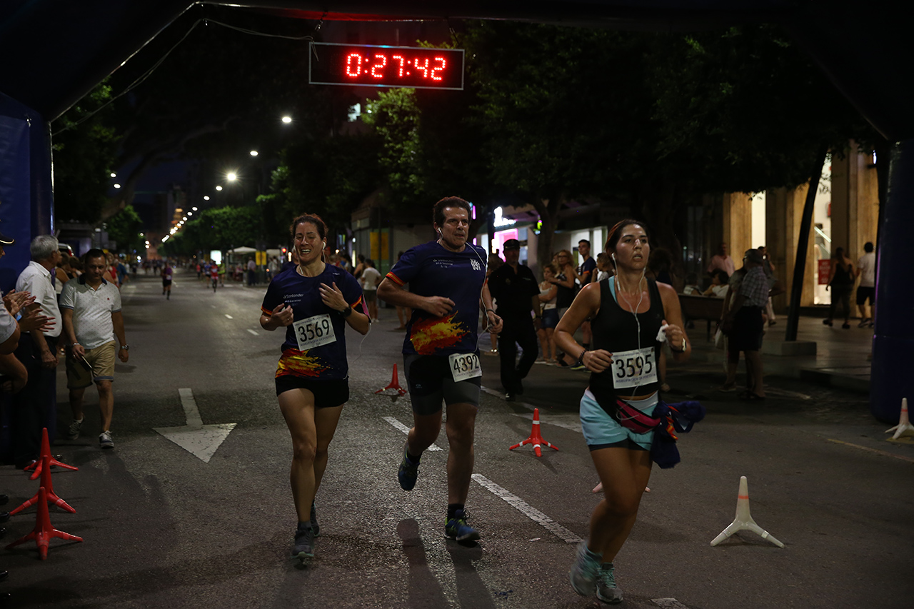 Primer plano de tres participantes, dos mujeres y un hombre, a la llegada a meta en la Carrera Nocturna del Día de la Policía.