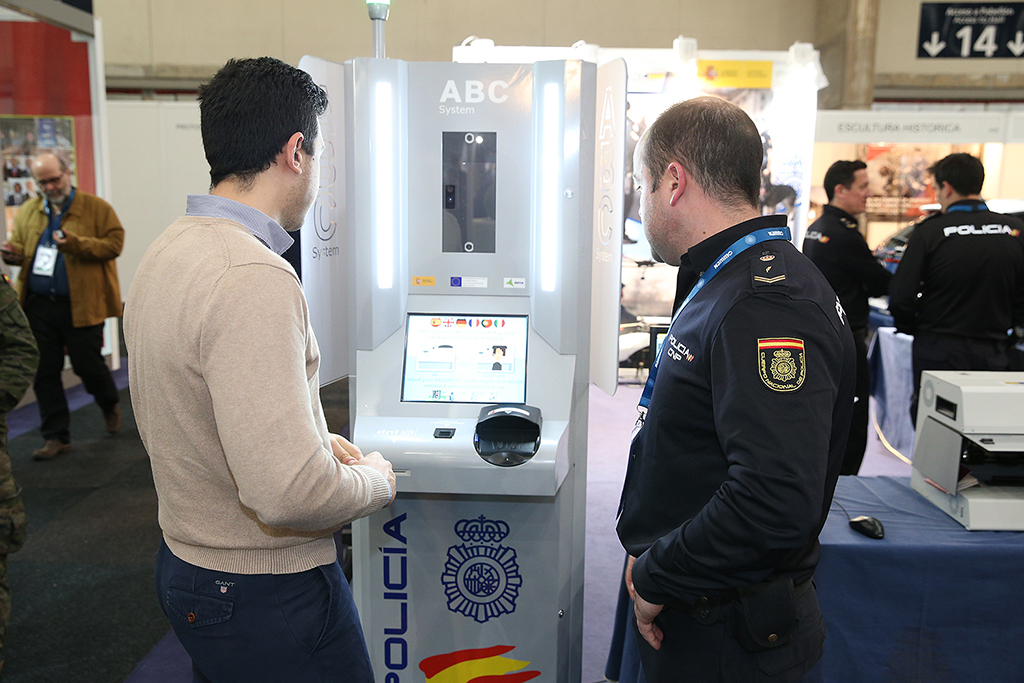Agente de policía mostrando a un visitante el kiosco con el sistema conocido como ABC System, para agilizar el cruce de fronteras.
