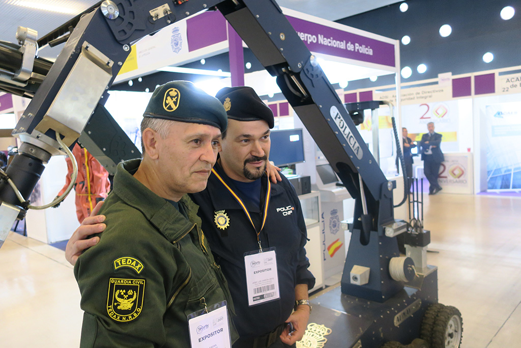Un miembro del TEDAX de la Guardia Civil y otro, del TEDAX de la Policía Nacional, posan delante de un robot para desactivar explosivos.