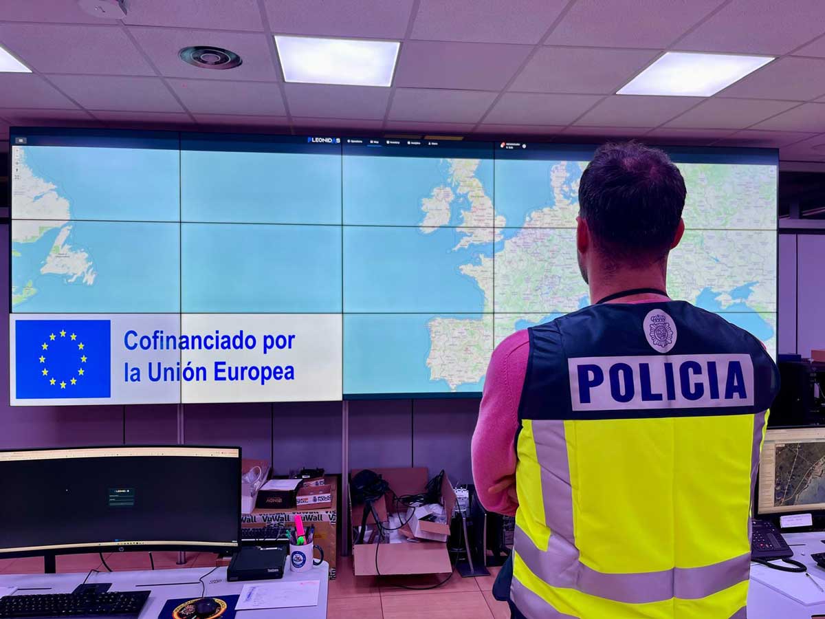 Policía de espaldas mirando una pantalla con un mapa de Europa y el Océano Atlántico